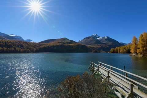 Wooden jetty on lake with sun in autumn