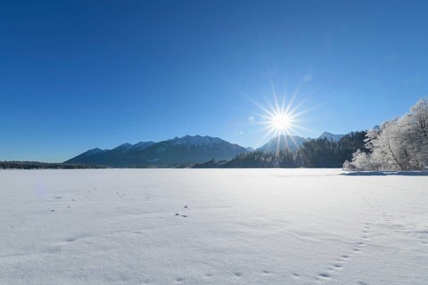 Frozen lake Barmsee with Karwendel mountainrange on morning with sun in winter
