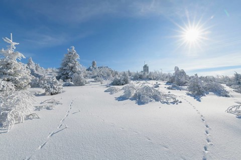 Snow covered winter landscape with sun Fichtelberghaus and weather station