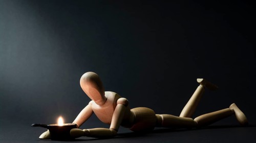 A mannequin is warmed by a fire