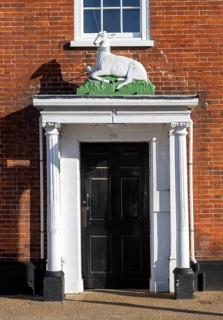 Historic sculpture of white hart deer above former entrance door to hotel