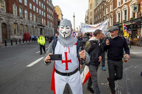 Man in St George uniform with mobile phone at a Leave means Leave march