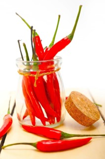 Red chili peppers on a glass jar over white wood rustic table