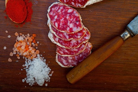Traditional Italian salame cured sausage sliced on a wood board