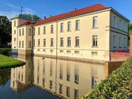 View of classicist castle Westerholt with reflection of building in historical moat
