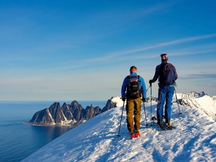 Two ski mountaineers at the summit of Husafjellet with a view over Devils Teeth