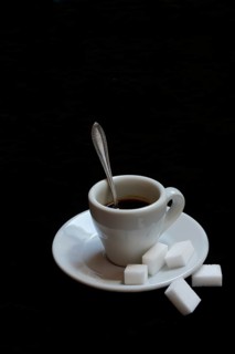 A cup of coffee with sugar cubes on a black background