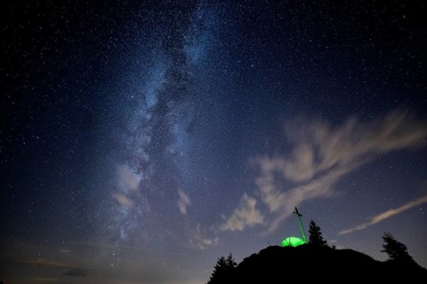 Green tent with summit cross under a starry sky on Portlakopf
