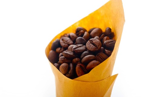 Espresso coffee beans on a paper cone cornucopia over white background