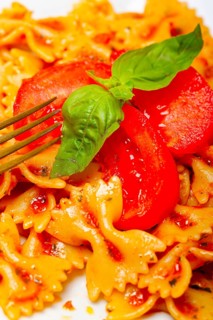 Italian pasta farfalle butterfly bow-tie with tomato basil sauce over white rustic wood table