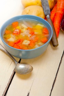 Traditional Italian minestrone soup on a rustic table with ingredients