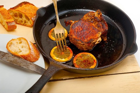 Pork chop seared on iron skillet with lemon and spices seasoning