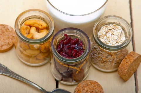 Healthy breakfast ingredients milk oat cashew nuts dried cramberry craisinns