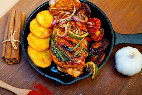 Roasted grilled BBQ chicken breast with herbs and spices rustic style on iron skillet