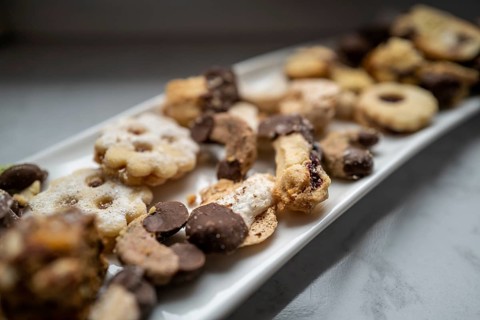 Sweet biscuits with chocolate coating lie on a rectangular white plate ready to be eaten