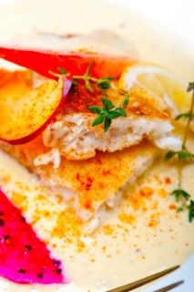 Sea bream orata fillet butter pan fried with fresh peach prune and dragonfruit slices thyme on top