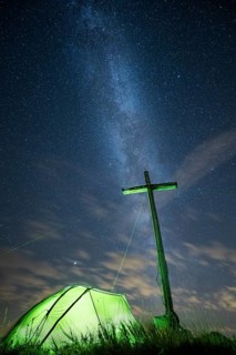 Green tent with summit cross under a starry sky on Portlakopf