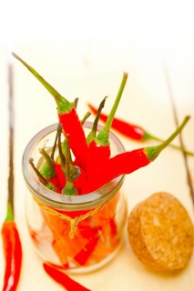 Red chili peppers on a glass jar over white wood rustic table