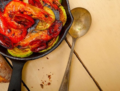 Roasted shrimps on cast iron skillet with zucchini and tomatoes