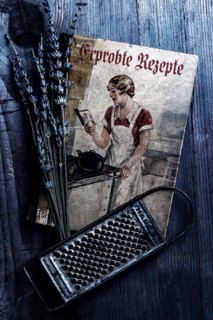 Old cookbook with lavender and kitchen grater on rustic background