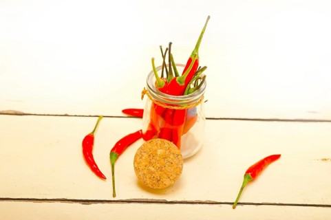 Red chili peppers on a glass jar over white wood rustic table