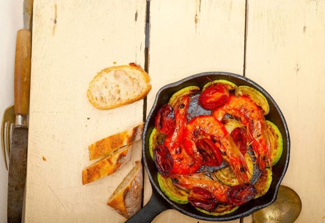 Roasted shrimps on cast iron skillet with zucchini and tomatoes