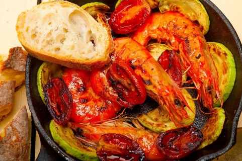 Roasted shrimps on cast iron skillet with zucchini and tomatoes