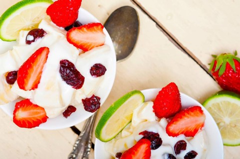 Fruit and yogurt salad healthy breakfast over white wood table