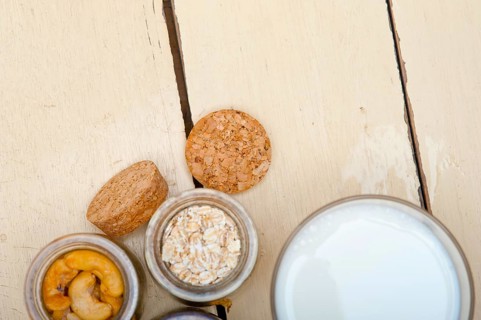 Healthy breakfast ingredients milk oat cashew nuts dried cramberry craisinns