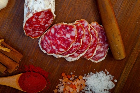 Traditional Italian salame cured sausage sliced on a wood board