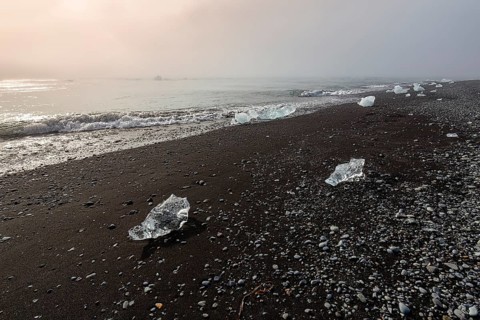 Ice crystals and pebbles on the black lava beach