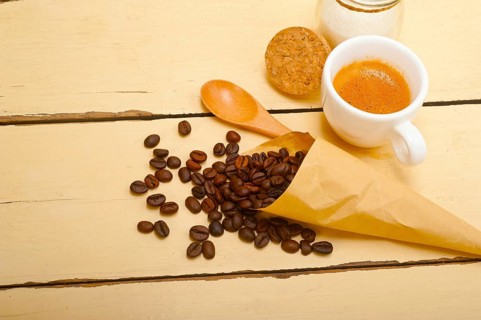 Espresso coffee and beans on a paper cone cornucopia over white background
