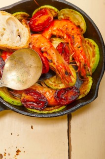 Roasted shrimps on cast iron skillet with zucchini and tomatoes