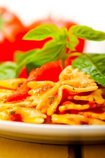 Italian pasta farfalle butterfly bow-tie with tomato basil sauce over white rustic wood table