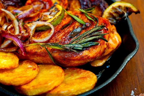 Roasted grilled BBQ chicken breast with herbs and spices rustic style on iron skillet