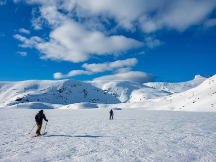 Two ski tourers crossing a frozen lake in the winter mountains