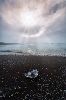 Ice crystal and pebbles on the black lava beach