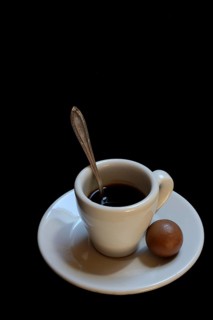A cup of coffee and chocolate praline on a black background