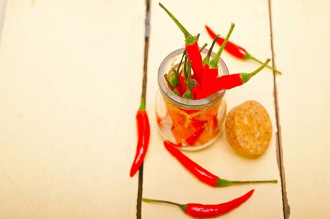 Red chili peppers on a glass jar over white wood rustic table