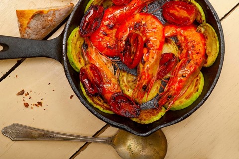 Roasted shrimps on cast iron skillet with zucchini and tomatoes