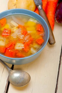 Traditional Italian minestrone soup on a rustic table with ingredients