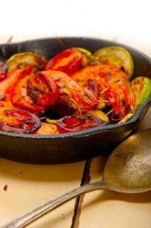 Roasted shrimps on cast iron skillet with zucchini and tomatoes