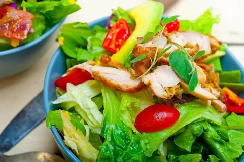 Fresh and healthy Chicken Avocado salad over rustic wood table