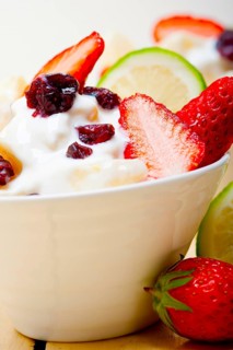 Fruit and yogurt salad healthy breakfast over white wood table
