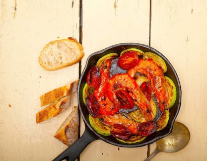 Roasted shrimps on cast iron skillet with zucchini and tomatoes