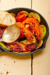 Roasted shrimps on cast iron skillet with zucchini and tomatoes