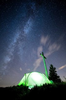 Green tent with summit cross under a starry sky on Portlakopf