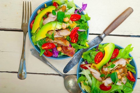 Fresh and healthy Chicken Avocado salad over rustic wood table