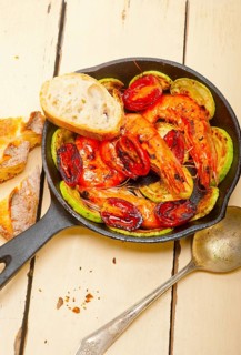 Roasted shrimps on cast iron skillet with zucchini and tomatoes