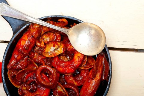 Fresh seafood stew prepared on an iron skillet ove white rustic wood table